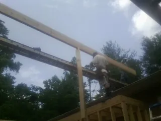 Carpenter setting a ridge beam over a new addition frame — Ice Dam Removal by Roofing Brothers in Basom