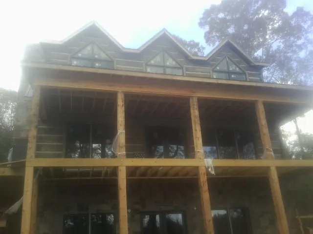 Dormers and porch framing on a large log home under construction — Roof Coating work by our crew in Basom