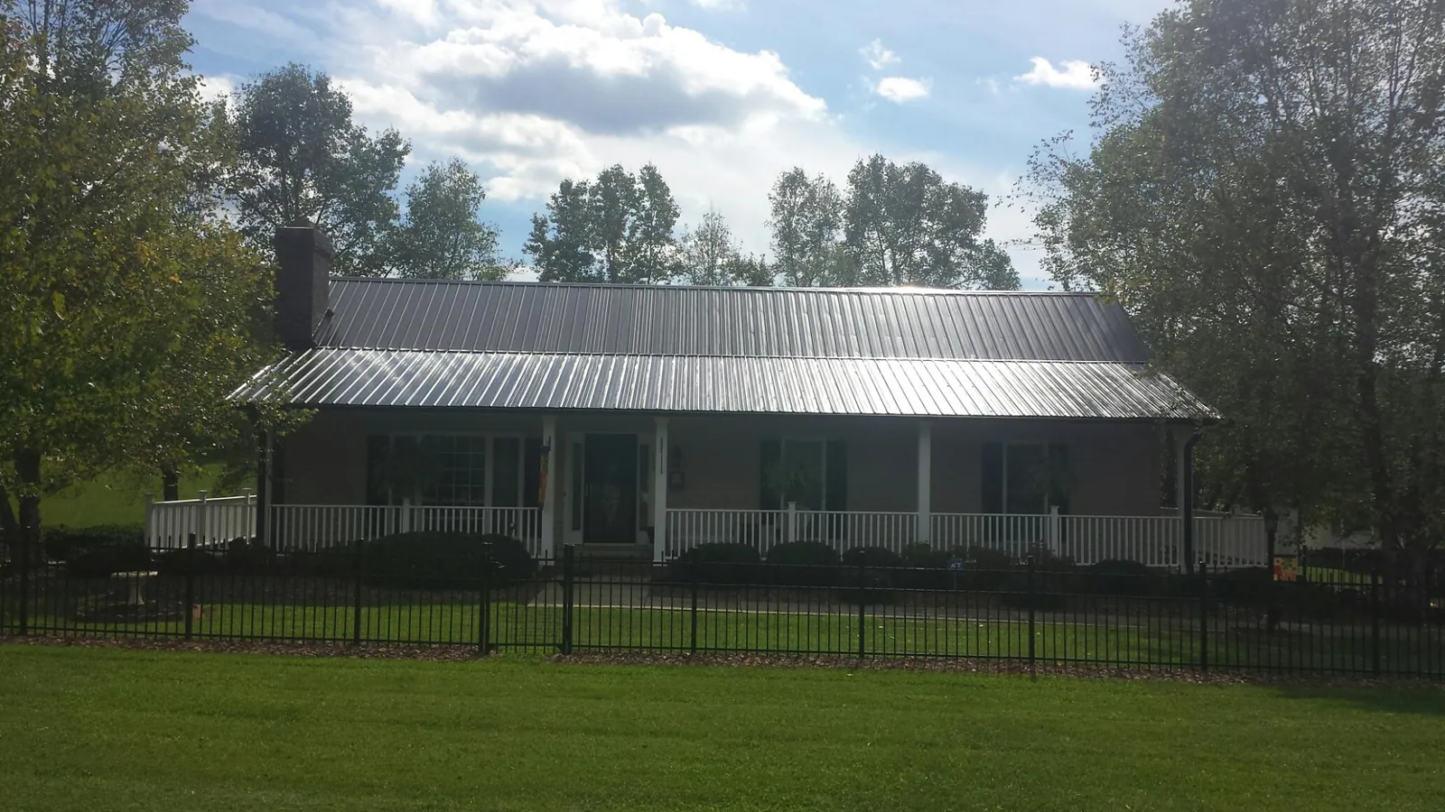 Gray metal roof on a brick ranch with a full width front porch — Gutter Guard Installation work by our crew in Basom