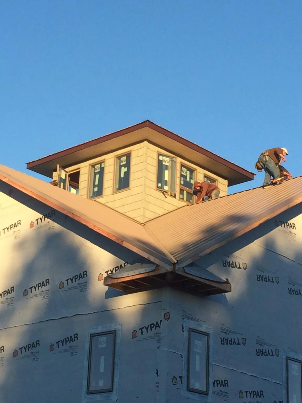 Roofers working around a rooftop cupola on a new metal roof at sunset — Roof Waterproofing in Basom by Roofing Brothers